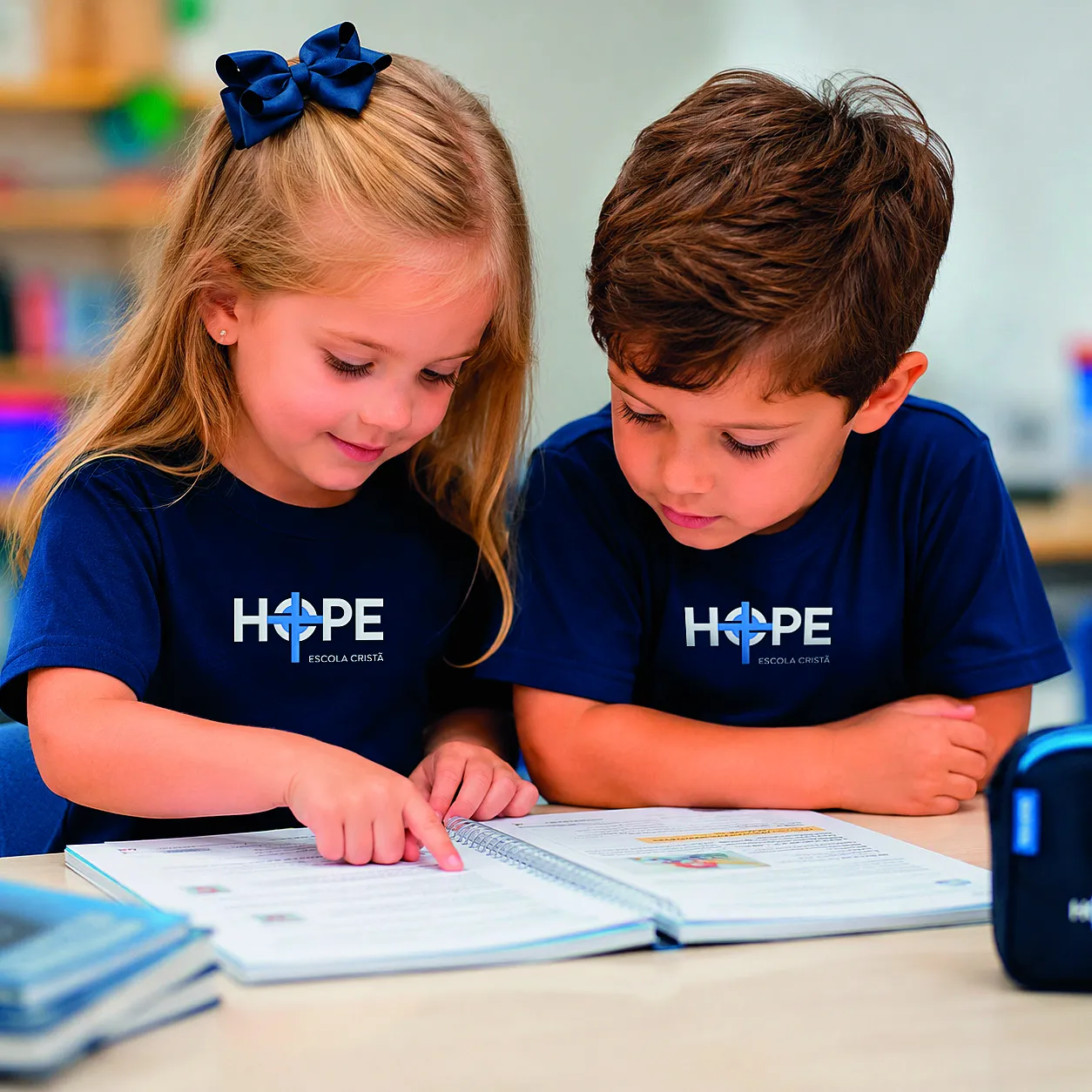 Duas crianças lendo um livro juntas, uniforme HOPE